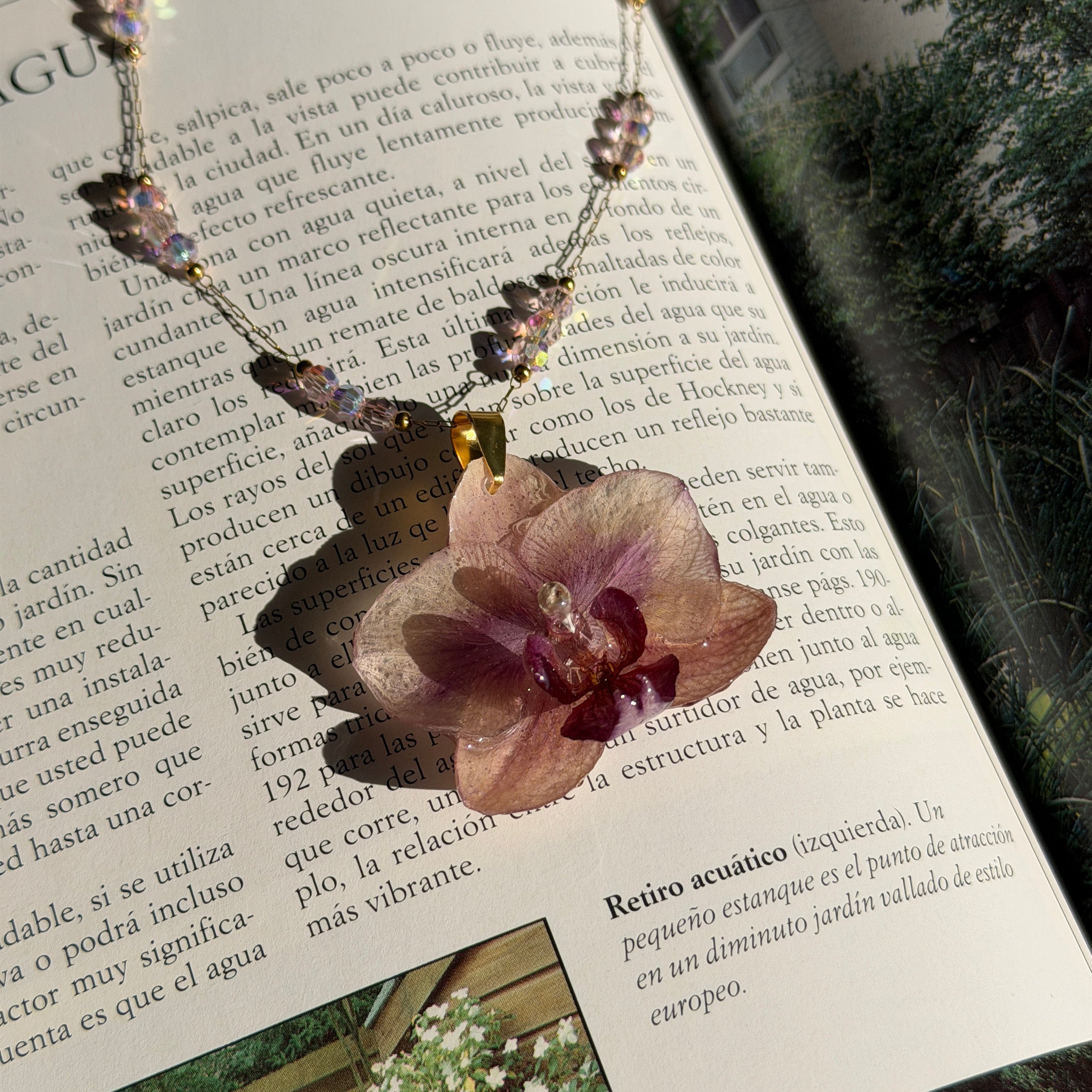 Collar con orquídea rosa y centro vino encapsulada en resina, capuchón de acero inoxidable