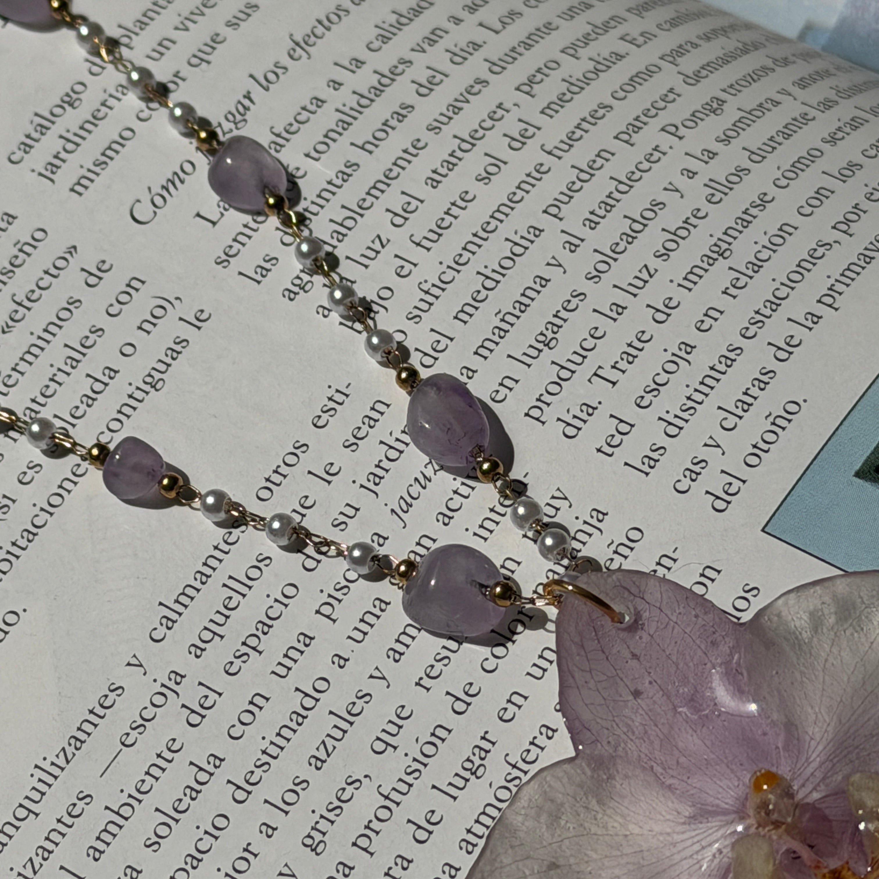 Detalle de las perlas y amatistas de la cadena junto al colgante de orquídea lila
