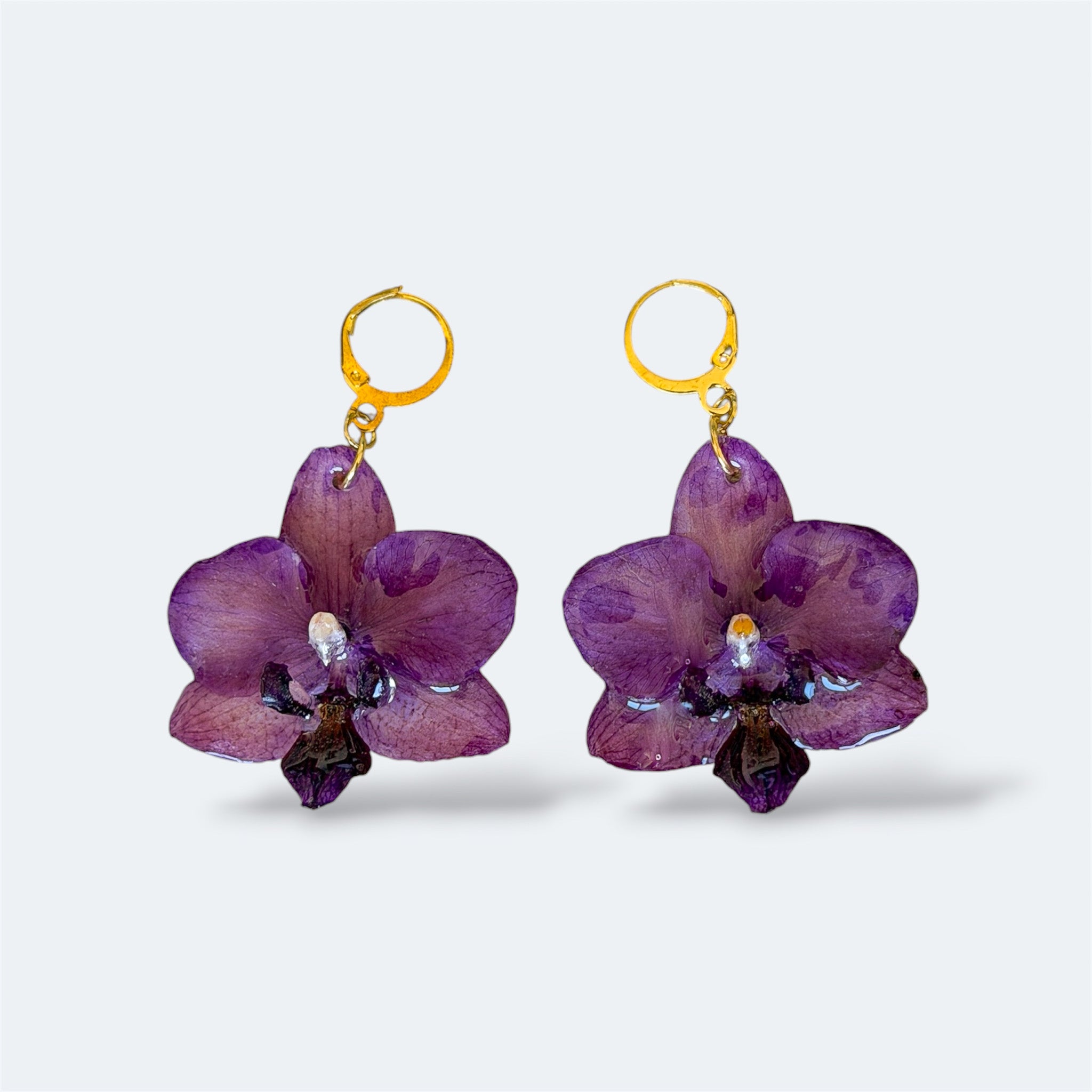 Pendientes con orquídea púrpura encapsulada en resina, sobre aros de acero inoxidable