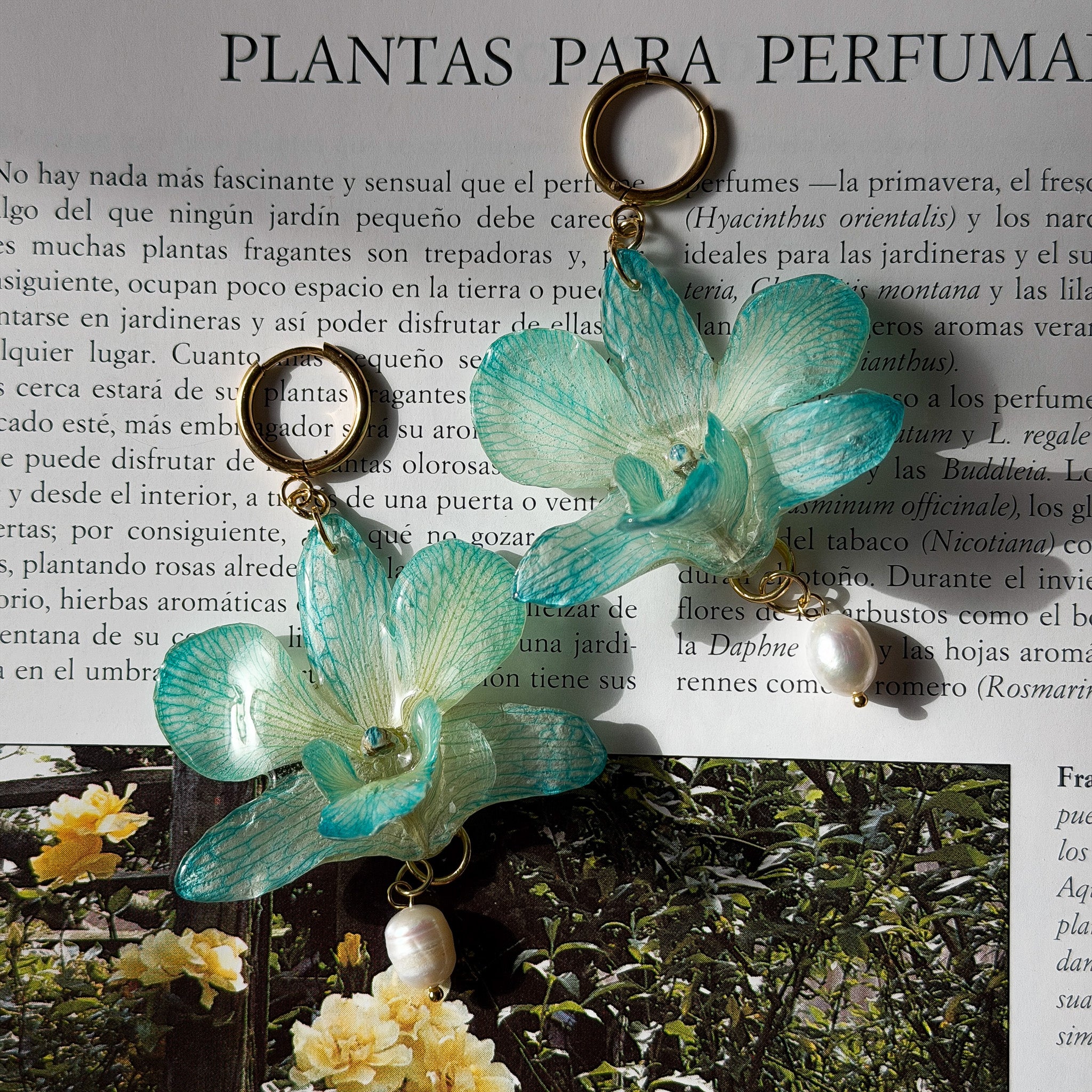 Detalle de orquídea turquesa real preservada en resina, vetas marcadas y perla natural de agua dulce