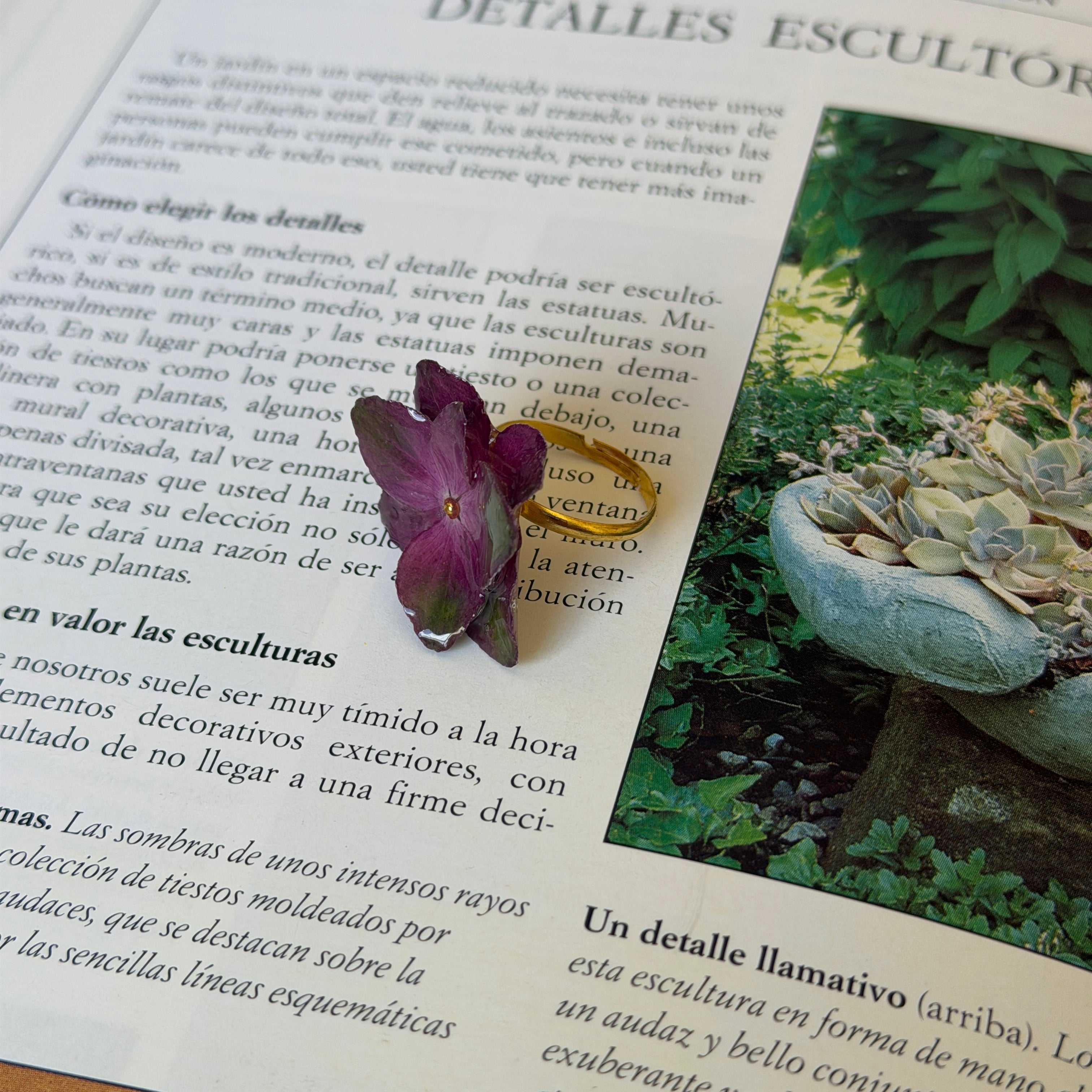 Anillo de hortensias magenta sobre aro ajustable de acero inoxidable, apoyado en un libro abierto