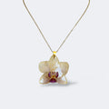 Collar con orquídea blanco marfil y labelo magenta encapsulada en resina, sobre cadena de acero inoxidable