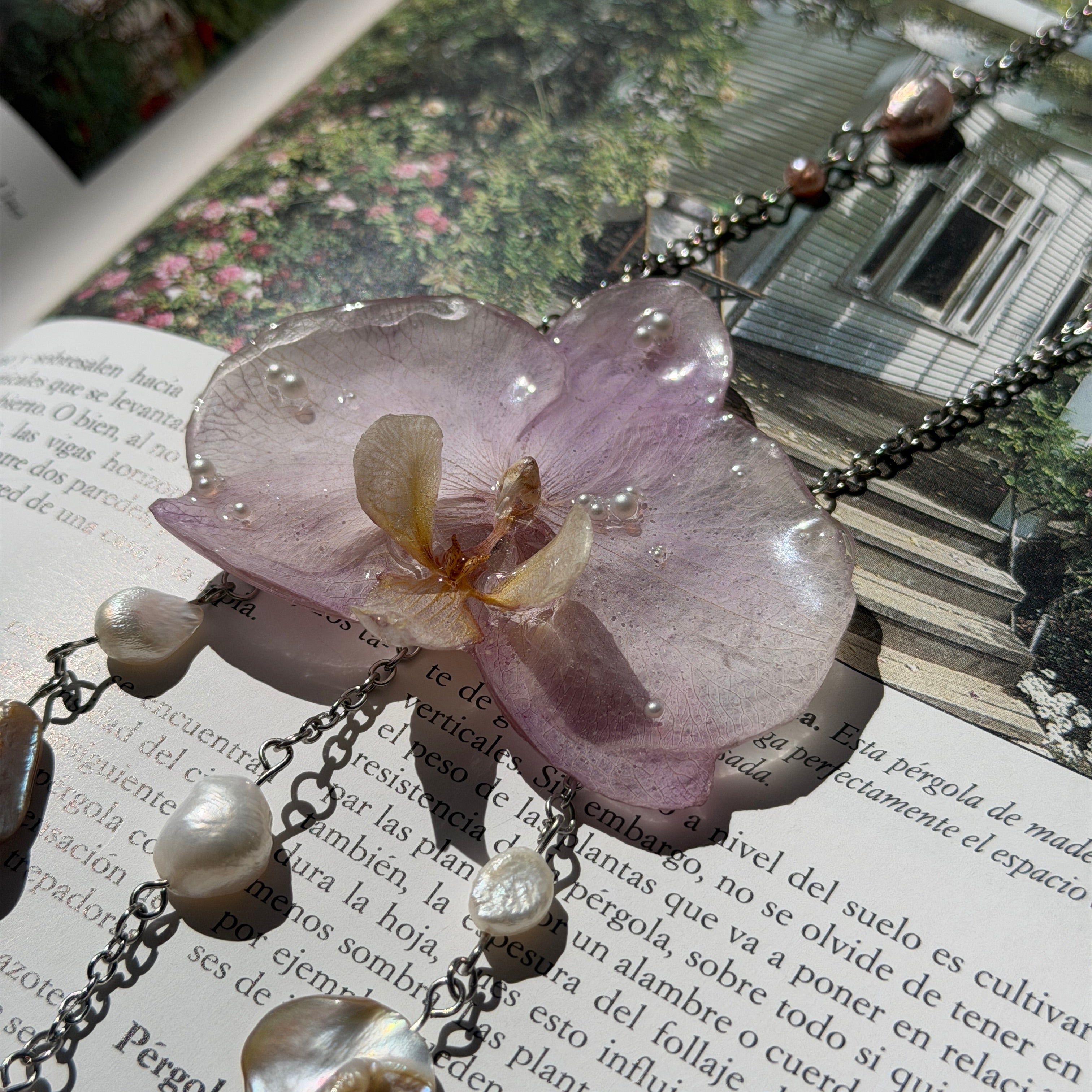 Detalle de orquídea lila real preservada en resina, con labelo crema y perlas diminutas incrustadas