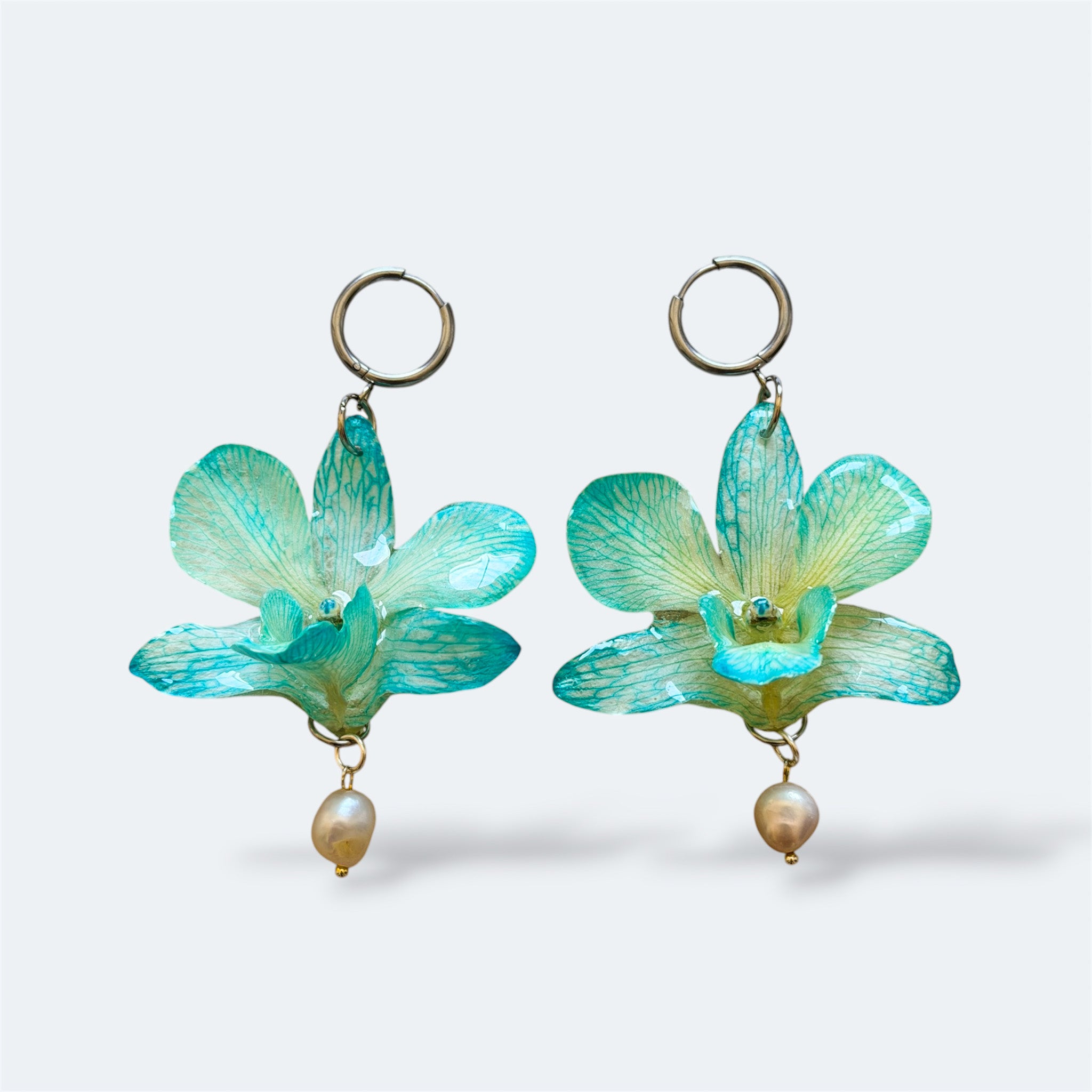 Pendientes con orquídeas Dendrobium turquesa encapsuladas en resina, sobre aro de acero inoxidable con perla colgante