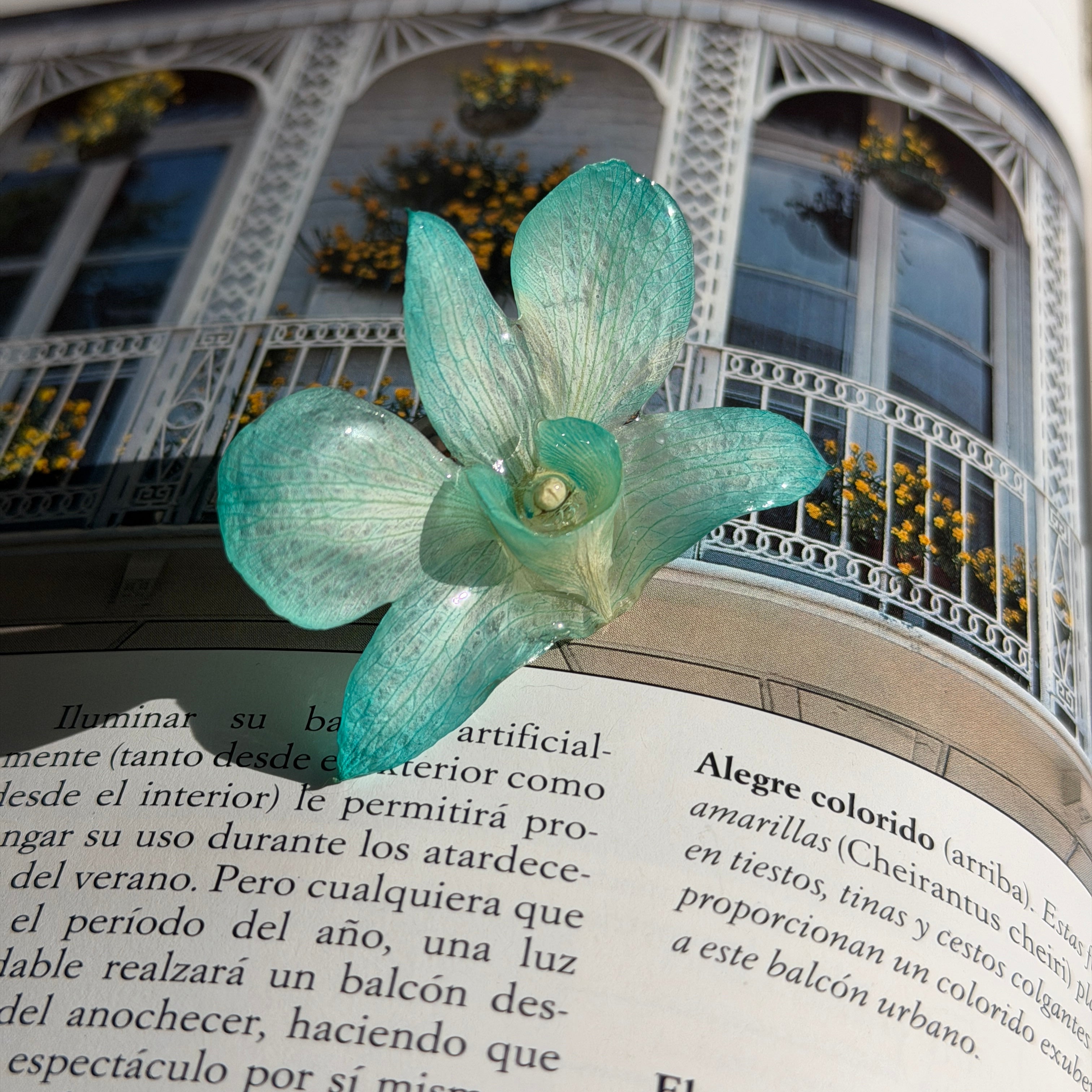 Detalle de orquídea turquesa real preservada en resina, con nervaduras marcadas y centro amarillo pálido