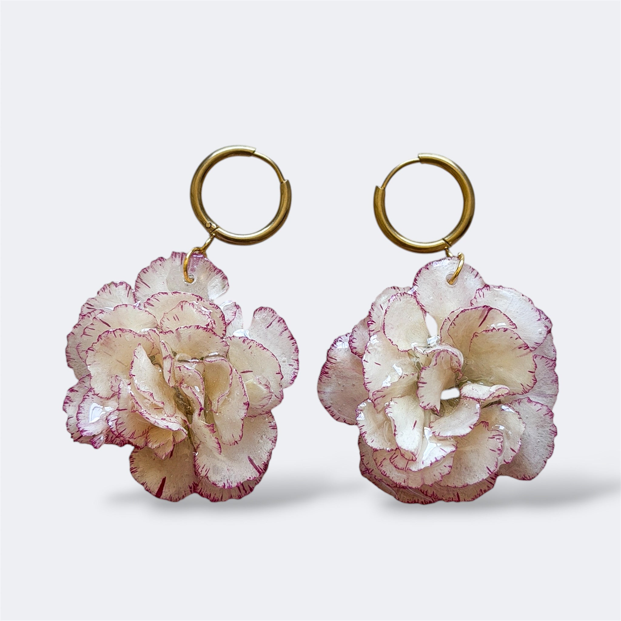Pendientes con clavel marfil y rosa claro encapsulado en resina, sobre aros de acero inoxidable