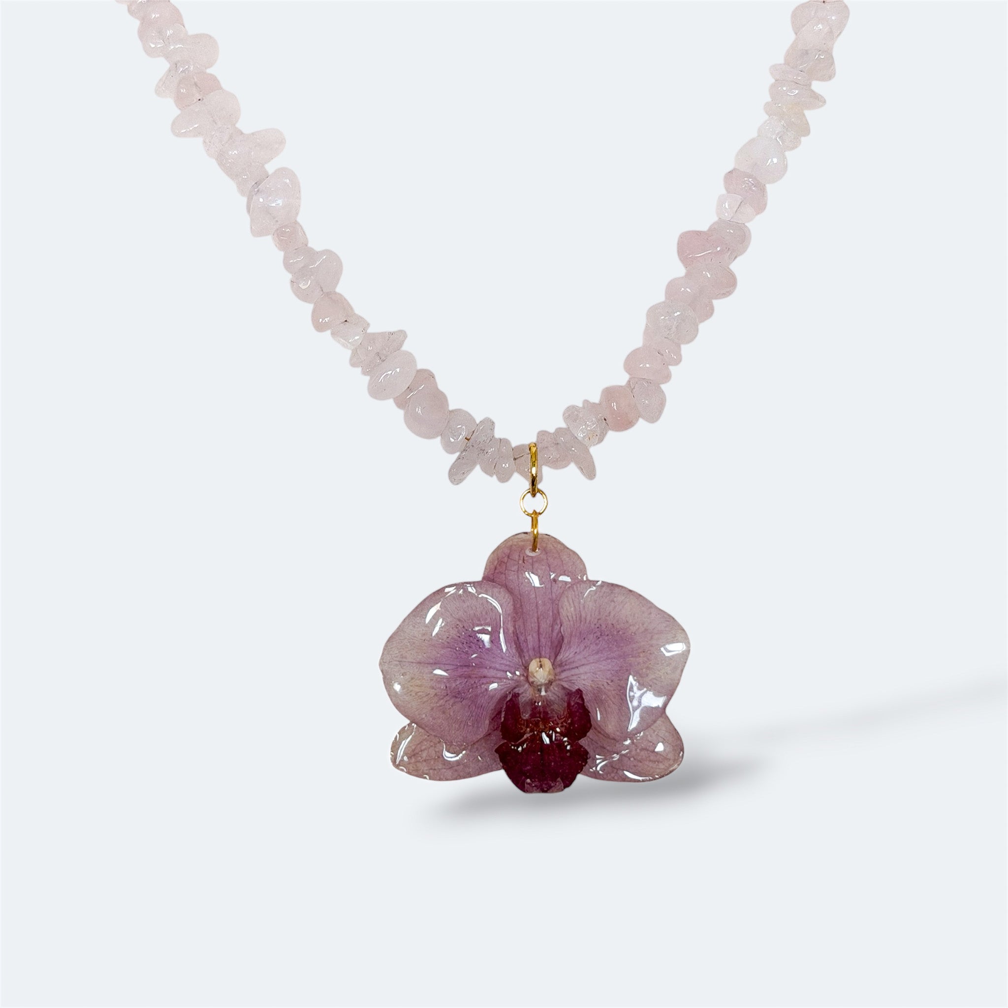 Collar con orquídea violeta encapsulada en resina, sobre hilo de cuarzo rosa