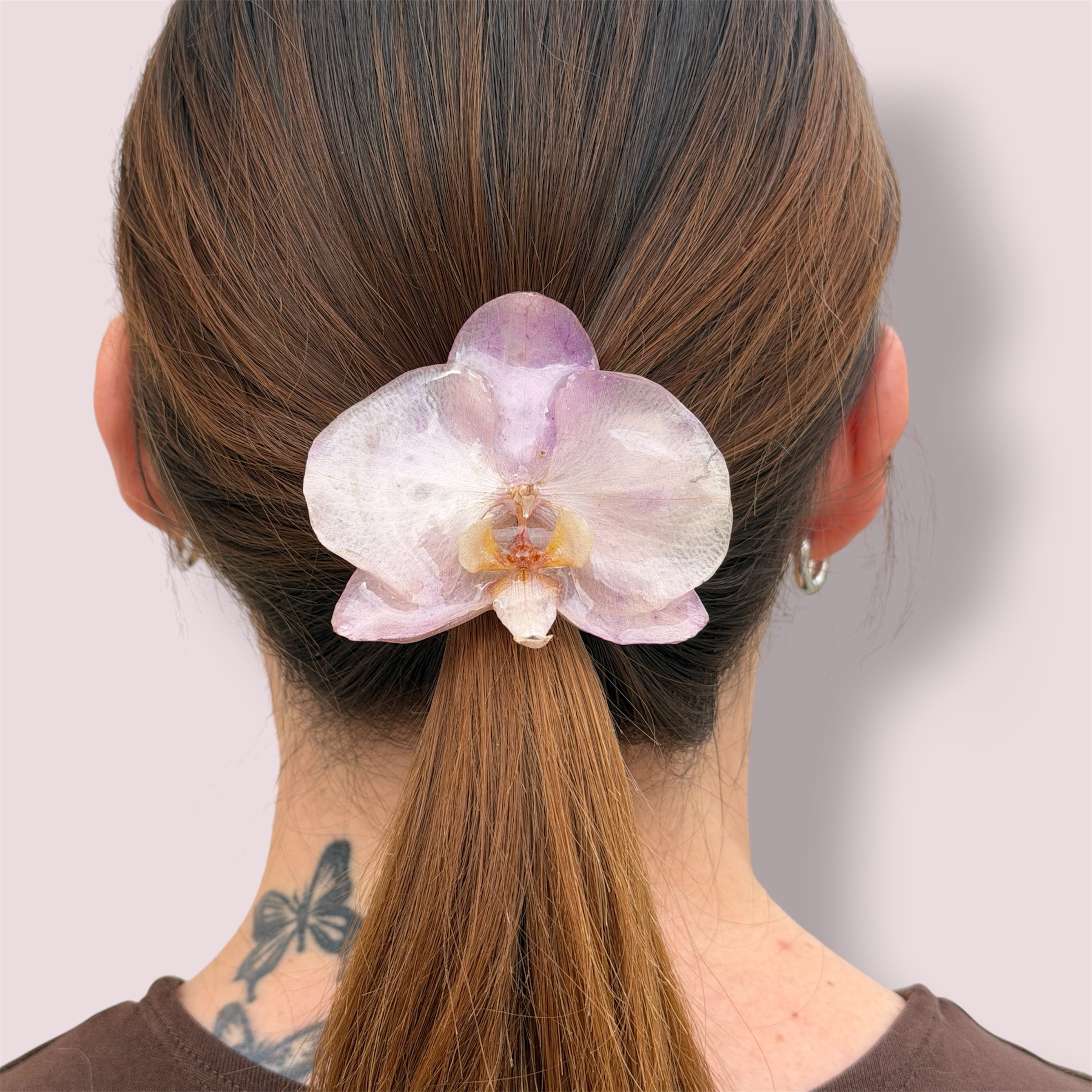 Mujer con pinza de orquídea lavanda preservada en resina sujetando el pelo recogido