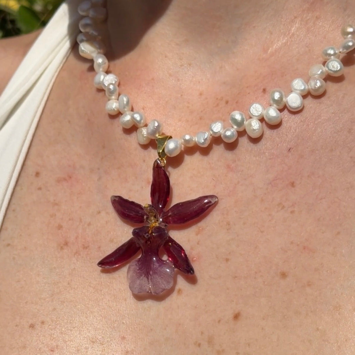 Primer plano de collar de orquídea Cambria burdeos encapsulada en resina sobre el escote