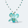 Collar con orquídea Dendrobium turquesa encapsulada en resina con perlas, sobre cadena de turquesas