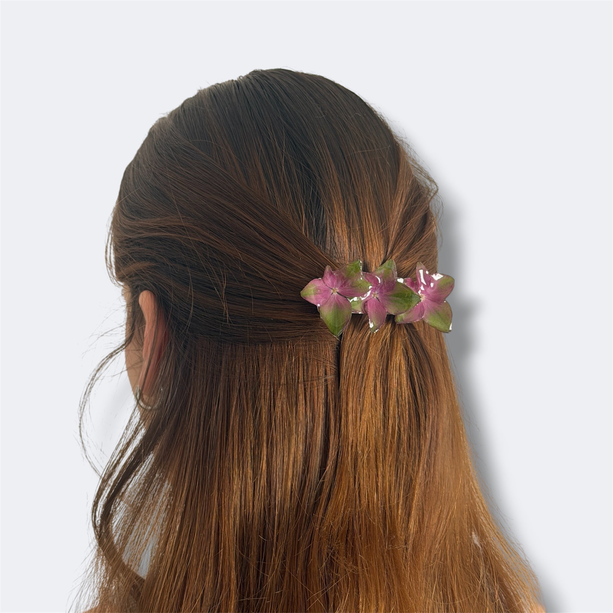 Mujer con pinza de tres hortensias fucsia y verde en resina recogiendo media melena