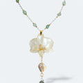 Collar con orquídea blanca encapsulada en resina, sobre cadena de acero inoxidable con piedras naturales verdes y perlas