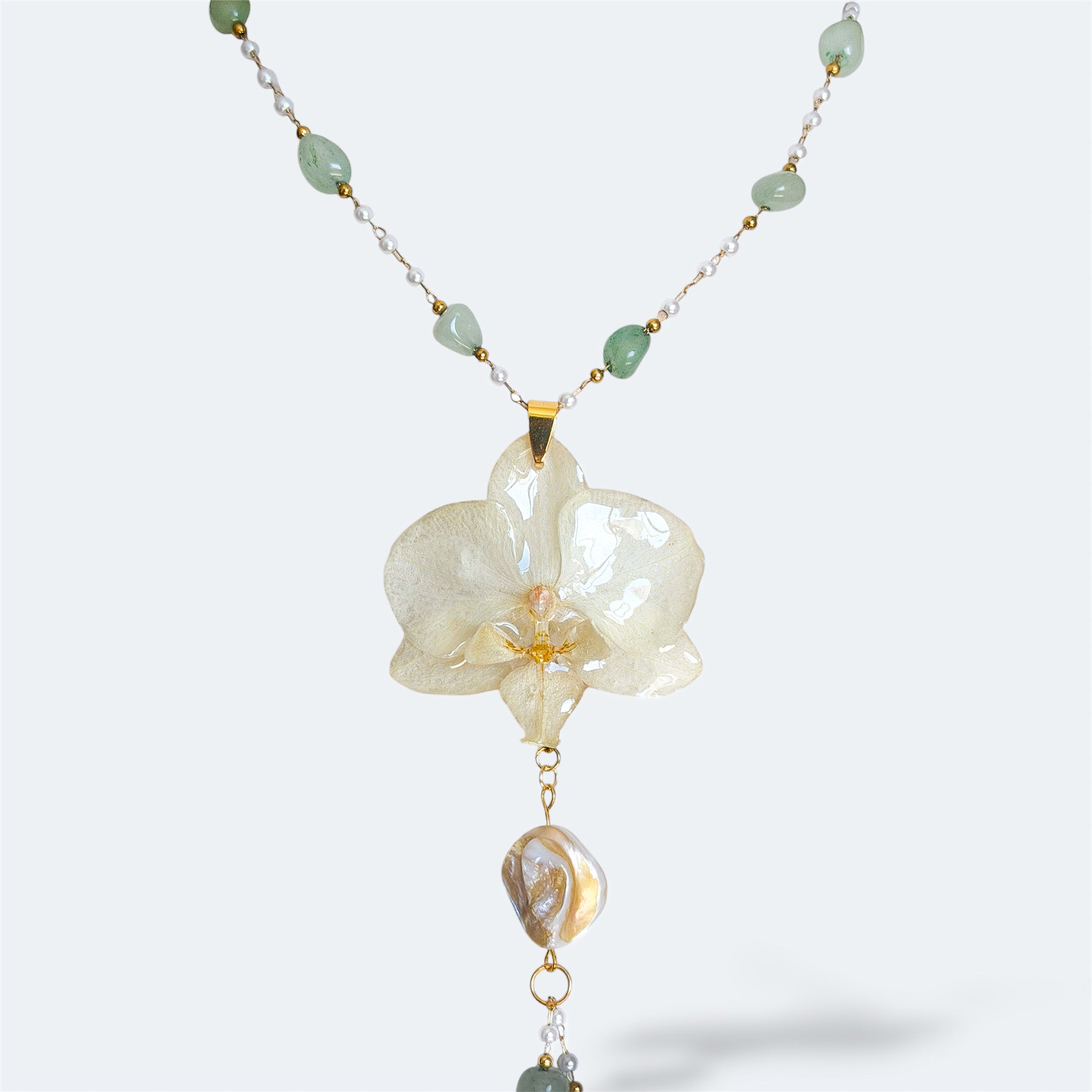 Collar con orquídea blanca encapsulada en resina, sobre cadena de acero inoxidable con piedras naturales verdes y perlas