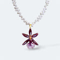 Collar con orquídea Cambria burdeos encapsulada en resina, sobre cadena de perlas naturales de agua dulce
