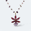 Collar con orquídea Cambria burdeos encapsulada en resina, sobre cadena de amatistas y acero inoxidable
