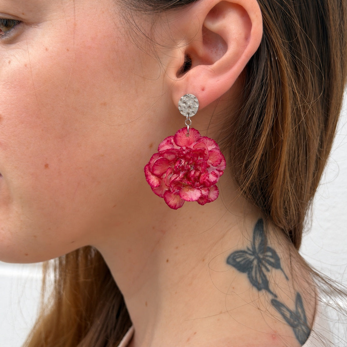 Pendientes Clavel Júpiter puestos, con botón martillado plateado